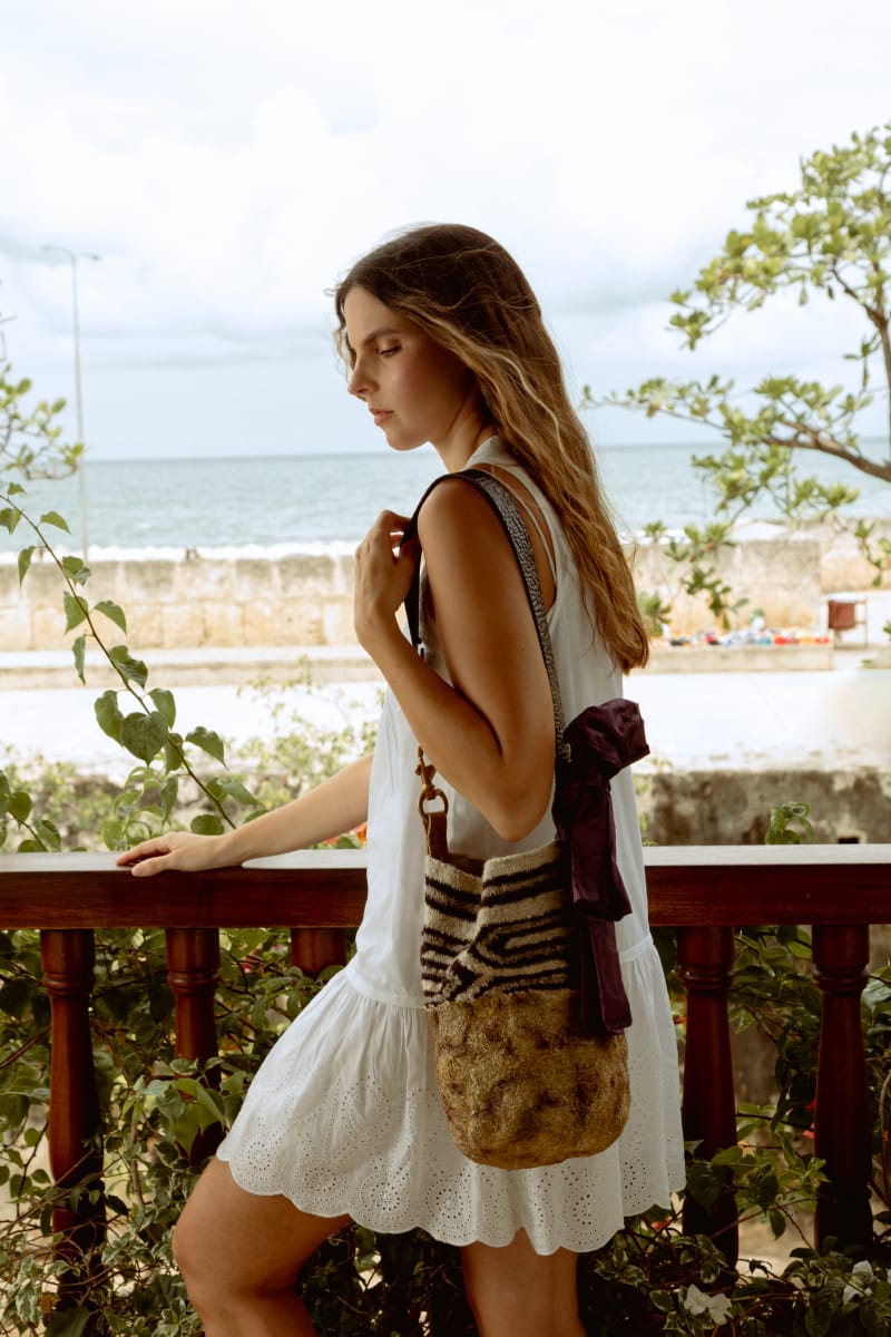 model posing with a large arhuaca handbag on a balcony in the center of cartagena